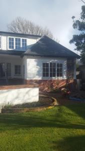 a white house with a black roof and a yard at 64Lewis in Invercargill