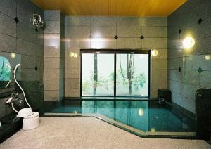a bathroom with a swimming pool with a large window at Hotel Route-Inn Mikawa Inter in Hakusan