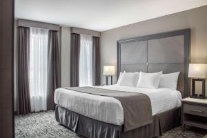 a hotel room with a large bed and two windows at Chateau Moncton Trademark Collection by Wyndham in Moncton