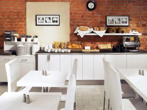 a restaurant with white tables and a brick wall at Ibis Styles Stockholm Odenplan in Stockholm