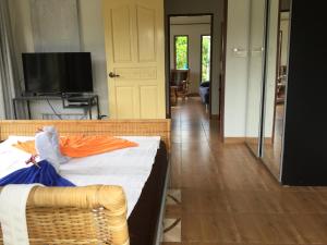 a room with a bed and a television and a door at Vacation House with tropical garden and private pool in Rayong