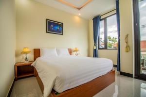 - une chambre avec un grand lit blanc et une fenêtre dans l'établissement Gold Stone Homestay, à Hội An