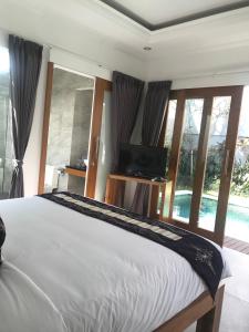 a bedroom with a bed and a tv and windows at Bali Villas Arta in Seminyak