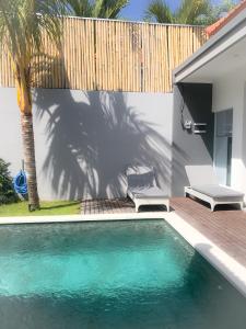 a swimming pool in front of a fence with a chair at Bali Villas Arta in Seminyak