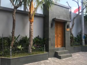 a building with a wooden door and a palm tree at Bali Villas Arta in Seminyak