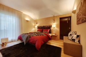 a bedroom with a large red bed and a window at Crioli Dolomiti Lodge in Villabassa