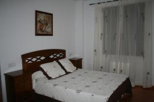 a bedroom with a bed with white sheets and curtains at Apartamentos Mirasierra in Coto Ríos