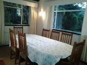 a dining room with a table and chairs and two windows at Ondini Guest House in Winterton