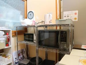a microwave on a metal rack in a kitchen at Guest House Minato in Miyako