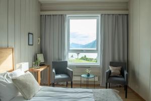 a bedroom with a bed and two chairs and a window at Skjolden Hotel in Skjolden