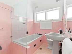 een roze badkamer met een bad en een wastafel bij Barrenjoey Beach House in Palm Beach