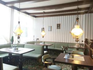 ein Esszimmer mit Tischen, Stühlen und Kronleuchtern in der Unterkunft Der Quellenhof in Helmstedt