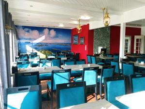a dining room with tables and blue chairs at Røst Bryggehotell in Røst