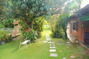 a yard with a white chair in the grass at Pousada Nasa in São Bento do Sapucaí