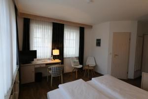 Schlafzimmer mit einem Bett und einem Schreibtisch mit einem Computer in der Unterkunft Hotel-Restaurant & Metzgerei Rößle in Dettingen an der Erms