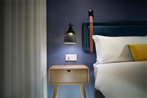 a bedroom with a bed and a nightstand with a lamp at Just Sleep - Ximending in Taipei