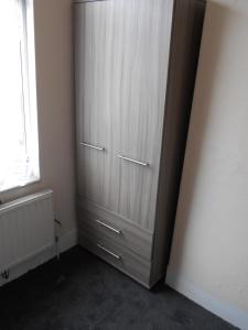 Habitación con ventana y armario con puertas blancas. en Cosy Homes, en Liverpool