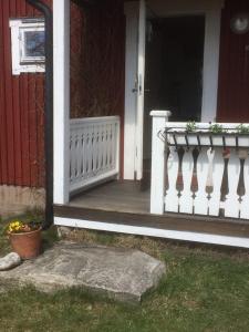un porche delantero de una casa con una barandilla blanca en Annies Hus en Årjäng