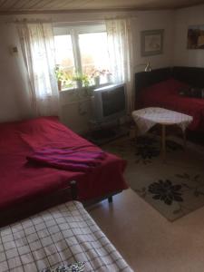 1 dormitorio con cama roja y TV en Annies Hus en Årjäng