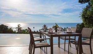 una mesa de comedor y sillas en un patio con vistas al océano en Eranda Pool Spa Villa, Chaweng Koh Samui- SHA Extra Plus, en Chaweng