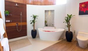 un bagno con vasca e 2 piante in vaso di Eranda Pool Spa Villa, Chaweng Koh Samui- SHA Extra Plus a Chaweng Beach