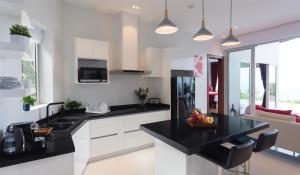 a kitchen with white cabinets and black counter tops at Eranda Pool Spa Villa, Chaweng Koh Samui in Chaweng