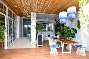 una sala da pranzo con tavolo, sedie e tavola da surf di Chill House at Naiyang a Nai Yang Beach