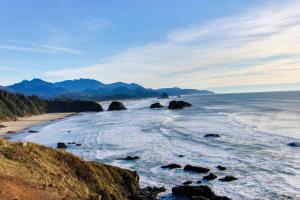 a view of a beach with rocks in the water at Beaches Inn | Pacific Surf Townhouse in Cannon Beach