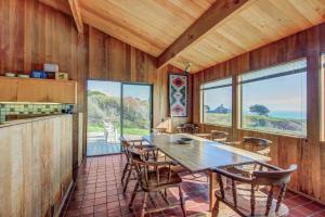 a dining room with a table and chairs and windows at Donaldson Escape in Sea Ranch