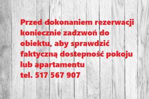 um sinal com escrita vermelha numa parede de madeira em Jaskółka - pokoje i apartament przy plaży em Olsztyn