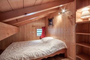 1 dormitorio en una cabaña de madera con cama y estanterías en LES SERMES M504, en Morzine