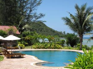 a swimming pool with a table and an umbrella at Malibu Beach Bungalows in Chaloklum