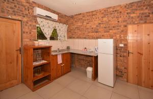 a kitchen with a white refrigerator and a brick wall at IRONWOOD LODGE in Pennington