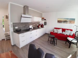 uma cozinha e uma sala de estar com um sofá vermelho em Ferienwohnung SteinReich em Glowe