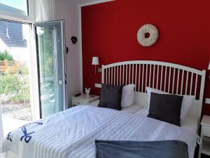 um quarto com uma cama branca e uma parede vermelha em Ferienwohnung SteinReich em Glowe