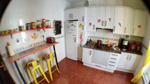 a small kitchen with white cabinets and yellow chairs at GoodHouse in Gijón