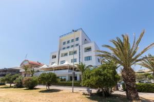 a white building with palm trees in front of it at Hotel Royal in Fermo