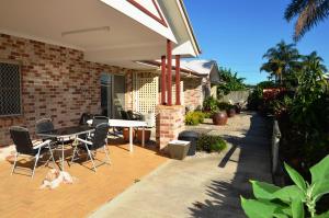 a patio with a table and chairs and a dog laying on the ground at Redland Bay Motel in Redland Bay