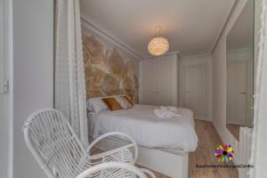 a small bedroom with a bed and a chair at Edificio Aptos Turisticos - Burgos Centro HC7 in Burgos