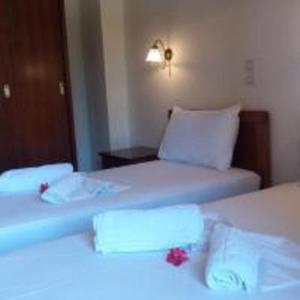 a room with two beds with white sheets and red flowers at Ζante Dolphin in Alykes