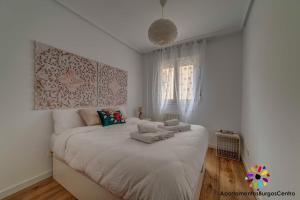 a white bedroom with a large bed with towels on it at Edificio Aptos Turisticos - Burgos Centro HC7 in Burgos