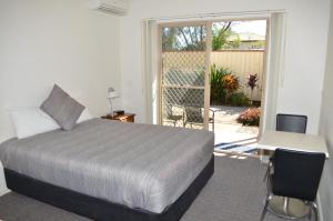 a bedroom with a bed and a desk and a patio at Redland Bay Motel in Redland Bay