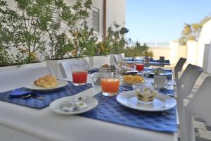 una mesa con platos de comida y vasos de zumo de naranja en Baia Azzurra B&B, en Torre Lapillo