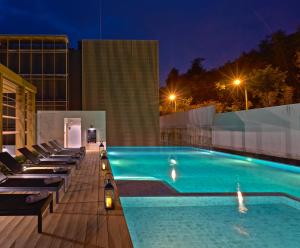 a swimming pool with lounge chairs on a building at night at Has Pattaya in Pattaya South