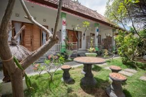 a garden with a table and stools in front of a house at Pondok Kana And Hostel by Ecommerceloka in Nusa Penida