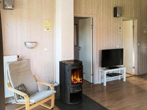 a living room with a fireplace and a chair and a television at Two-Bedroom Holiday home in Otterndorf 4 in Otterndorf