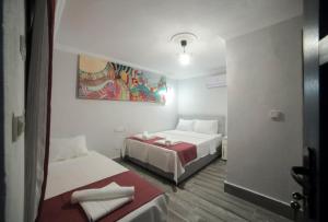 Habitación con 2 camas y una pintura en la pared. en Assos Yalı Butik Otel Beach en Ahmetçe