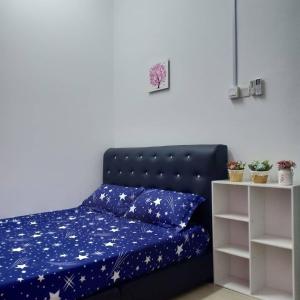 愛極樂的住宿－Ana Homestay Ayer Keroh Melaka，一张带蓝色棉被和枕头的床