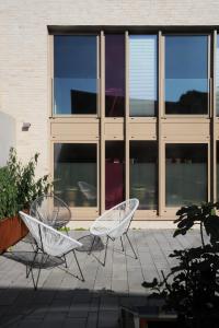 2 chaises blanches assises devant un bâtiment dans l'établissement Studio Feuerfest, à Hambourg