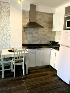 uma cozinha com armários brancos, uma mesa e um frigorífico em El paradis em Lloret de Mar